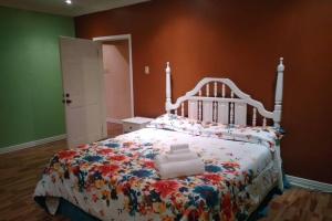 um quarto com uma cama branca e uma colcha floral em Ocho Rios Hideaway em Ocho Rios