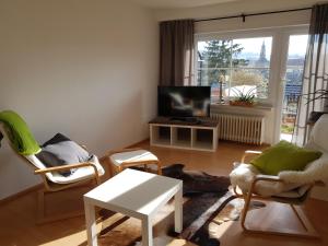 sala de estar con sillas, mesa y TV en Ferienwohnung Kraichgaublick, en Angelbachtal