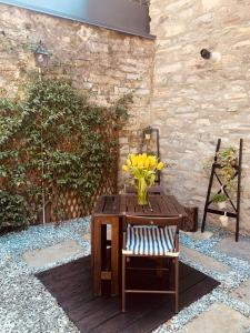 wazon z żółtych kwiatów siedzący na stole z krzesłem w obiekcie Il borghetto di Torno w mieście Torno