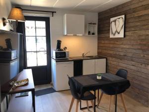 una pequeña cocina con mesa y sillas en una habitación en Le petit studio de l'espace bien être, en Libin