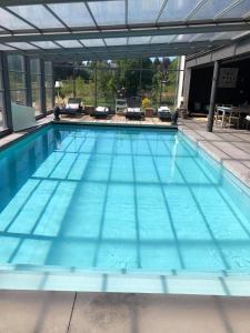 a large swimming pool with blue water at Le petit studio de l'espace bien être in Libin