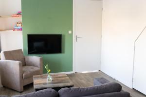 sala de estar con sofá, sillas y TV en State Klaver Vier en Hollum