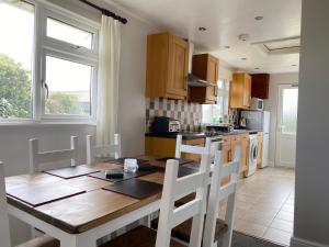 a kitchen with a wooden table and white chairs at Copthorne - Tintagel in Tintagel