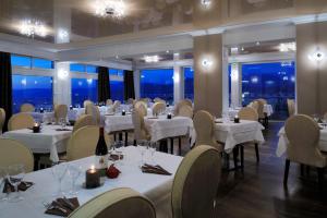 a restaurant with white tables and chairs and windows at Hotel Des Roches in Sartène