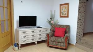 uma sala de estar com uma cadeira e uma televisão numa cómoda em Casa Rural Casa La Abuela em Belmonte