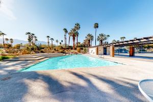 a swimming pool with palm trees and a building at Poolside Getaway Permit# 4610 in Palm Springs