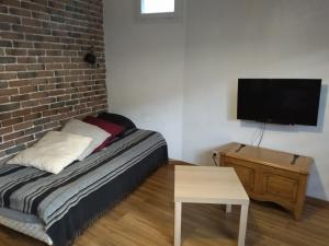 - une chambre avec un lit et une télévision sur un mur en briques dans l'établissement Aurillac meuble de tourisme, à Aurillac