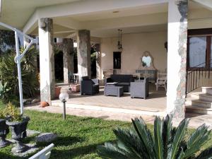 a house with a patio with a couch and chairs at Villa sullo stretto in SantʼAgata