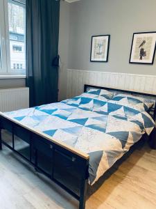 een bed met een blauwe en witte quilt bij Apartamenty ToTuGdynia 7 in Gdynia