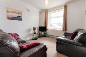 a living room with two leather couches and a television at River House with Parking - TV in Every Bedroom! in Loughor