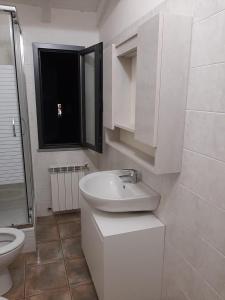 Baño blanco con lavabo y aseo en Casa Bach, en Piacenza