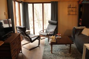 een woonkamer met 2 stoelen en een bank bij Boschalet op de veluwe in Laag-Soeren