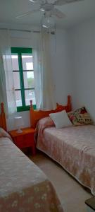 1 dormitorio con 2 camas y ventana en Primera linea de playa "Barrosamar", en Chiclana de la Frontera