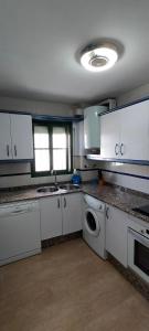 a kitchen with white cabinets and a sink and a dishwasher at Primera linea de playa "Barrosamar" in Chiclana de la Frontera