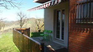 una veranda con due sedie verdi su una casa di La vedetta del Montefeltro a Peglio