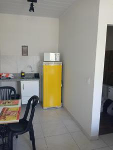 a yellow refrigerator in a kitchen with a table and chairs at Loft agradável em João Pessoa, PB in João Pessoa