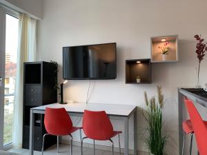 cocina con mesa con sillas rojas y TV en la pared en Exklusive Wohlfühloase by Rabe - Parkplatz & free Netflix & Coffee-Bar en Karlsruhe