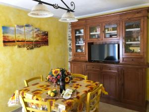 una sala da pranzo con tavolo e TV di Casa Il Gallo a Castellina Marittima