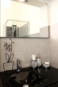 La salle de bains est pourvue d'un lavabo noir et d'un miroir. dans l'établissement B&B Ca' Nobil, à Bernate Ticino