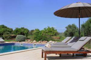 a group of lounge chairs with an umbrella next to a pool at Quinta da Luz - A Luxury Boutique B&B in Silves