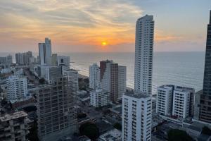 een zonsondergang boven een stad met hoge gebouwen en de oceaan bij Infinitum Bocagrande-Piso 26-Apartamento Nuevo in Cartagena