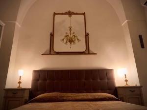 ein Schlafzimmer mit einem Bett mit einem Spiegel und 2 Lampen in der Unterkunft Dimora luxury Santa Lucia Apartaments in Galatone