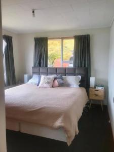 een slaapkamer met een groot bed en een raam bij Harbour Side Views in Dunedin