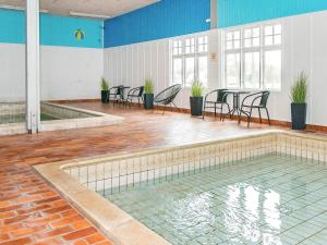 a swimming pool with chairs and a table in a room at 6 person holiday home in H jer in Højer