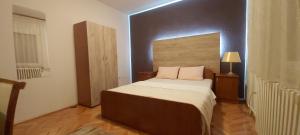 a bedroom with a large bed with a wooden headboard at Apartman EXCLUZIV in Prijedor