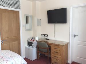 a hotel room with a desk with a television on the wall at Ivy House in Ickenham