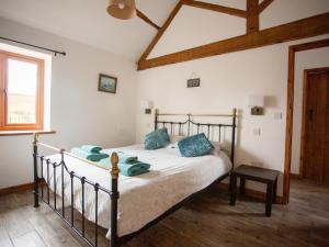 a bedroom with a bed with blue pillows on it at 1 Beacon View Barn in Felindre