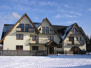 a large white house with a black roof in the snow at Willa Ewa in Poronin