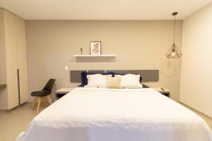 a bedroom with a white bed and a black chair at Lofts Santa Fe in Guadalajara