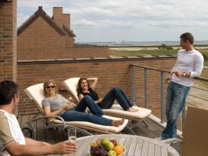 un groupe de personnes assises sur un balcon dans l'établissement 4 person holiday home on a holiday park in R m, à Sønderby