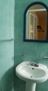 La salle de bains est pourvue d'un lavabo blanc et d'un miroir. dans l'établissement El Portón de Cortés, à Tepeaca