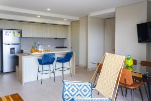 a kitchen with blue chairs and a kitchen with a refrigerator at La Boquilla 4 personas frente a la playa in Cartagena de Indias