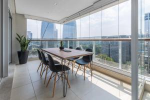 a table and chairs in a room with large windows at Charlie One Eleven Vila Olímpia in Sao Paulo