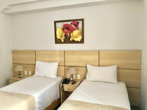 um quarto de hotel com duas camas e uma foto na parede em Hotel OK no Rio de Janeiro