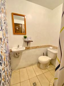 a bathroom with a toilet, sink, and mirror at Hostal Casa Tenango in Cobán