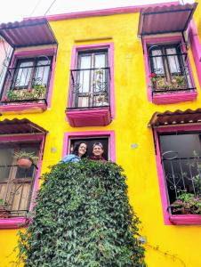 duas pessoas olhando para fora de uma janela de um edifício amarelo em Posada "Jardin Huasteca Xilitla" em Xilitla