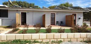 a small white house with a brick wall at Green Head Caravan Park in Green Head