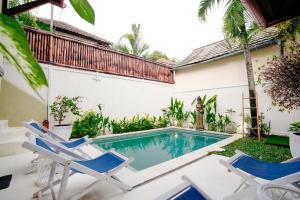 a swimming pool with chairs and a house at Villa Dewi in Seminyak