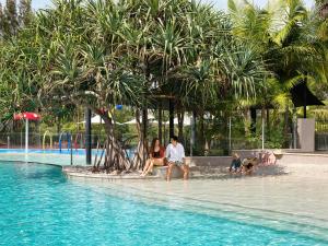 eine Gruppe von Personen, die am Rande eines Pools sitzen in der Unterkunft RACV Noosa Resort in Noosa Heads