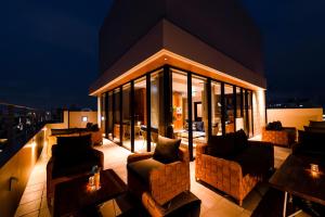 a rooftop patio with couches and tables at night at PROSTYLE TERRACE NAHA in Naha
