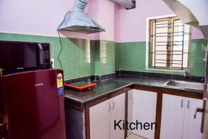 uma cozinha com um frigorífico vermelho e um lavatório em Ruby by Olys Apartment em Calcutá
