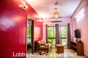uma sala de estar com uma parede vermelha com um espelho em Ruby by Olys Apartment em Calcutá