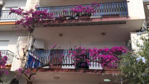 un balcón con flores púrpuras en un edificio en Taormina Sea house, en SantʼAlessio Siculo