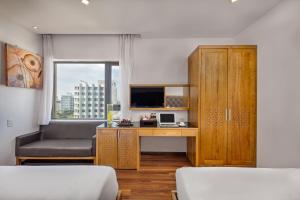 a bedroom with a desk and a chair and a television at Bliss Luxury Hotel in Da Nang