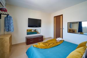 een slaapkamer met een blauw bed en een televisie bij La Macarena Airport in Málaga