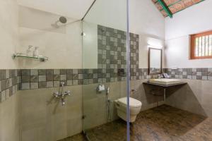 a bathroom with a shower and a toilet and a sink at amã Stays & Trails, Rare Earth Estate in Madikeri +45 photos